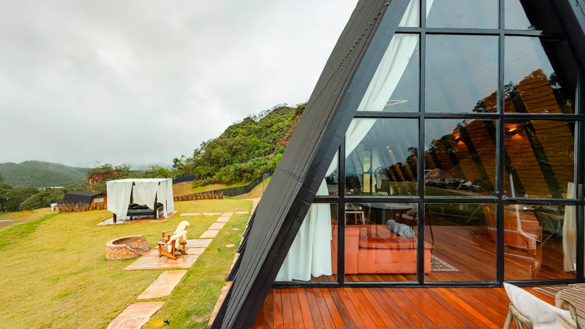 Chalé A-Frame com fachada de vidro e jardim com mirante